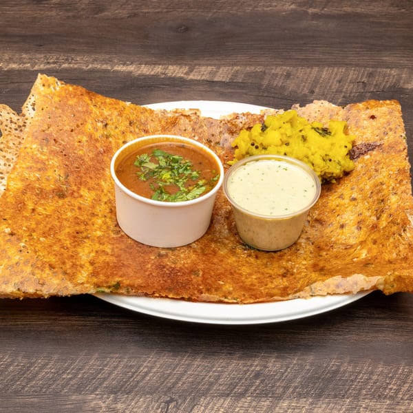 Crispy dosa with sambar, coconut chutney, and potato masala on a white plate.