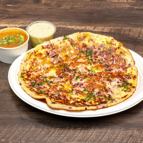 Onion Dosa from Dosa Spot, served with two dipping sauces on a wooden table.